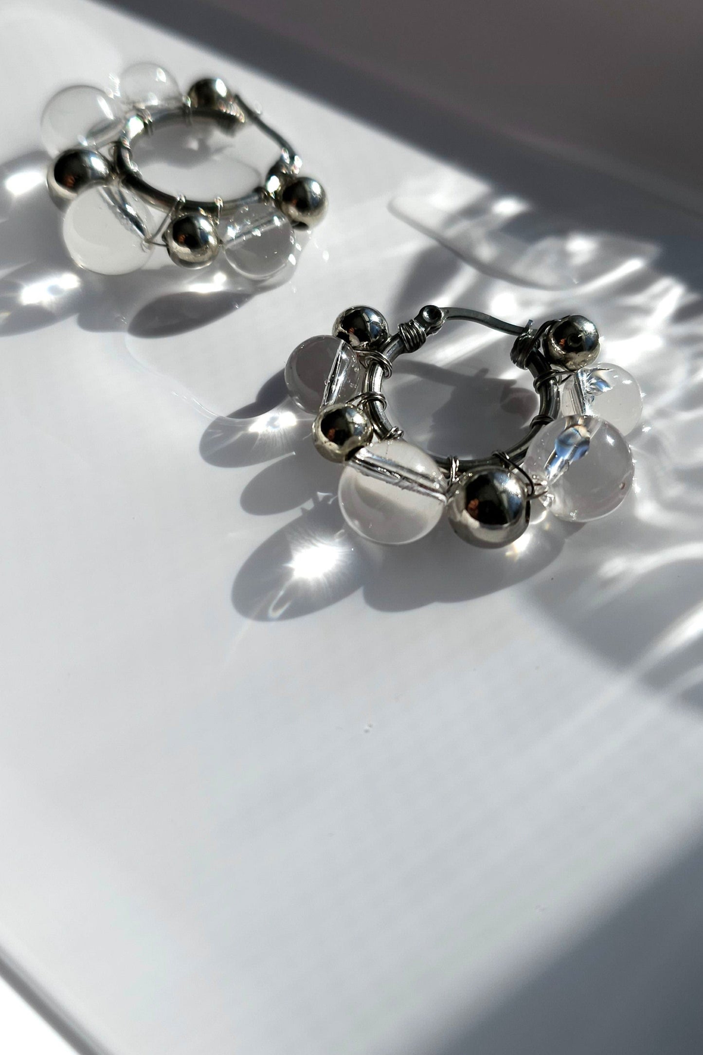 Close-up of GINRO hoop earring, featuring clear and silver orbs.