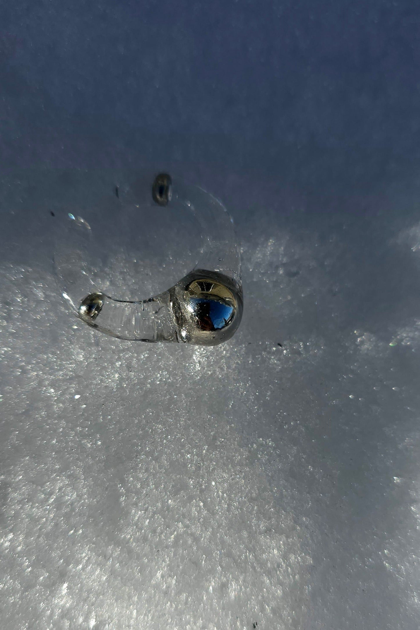 MITSUKI silver ring, clear band with silver orb in the center, on snowy surface.