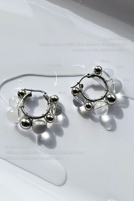 GINRO hoop earring with hand-molded clear orb and silver orb, showcasing the silver version and clear version on flat surface.