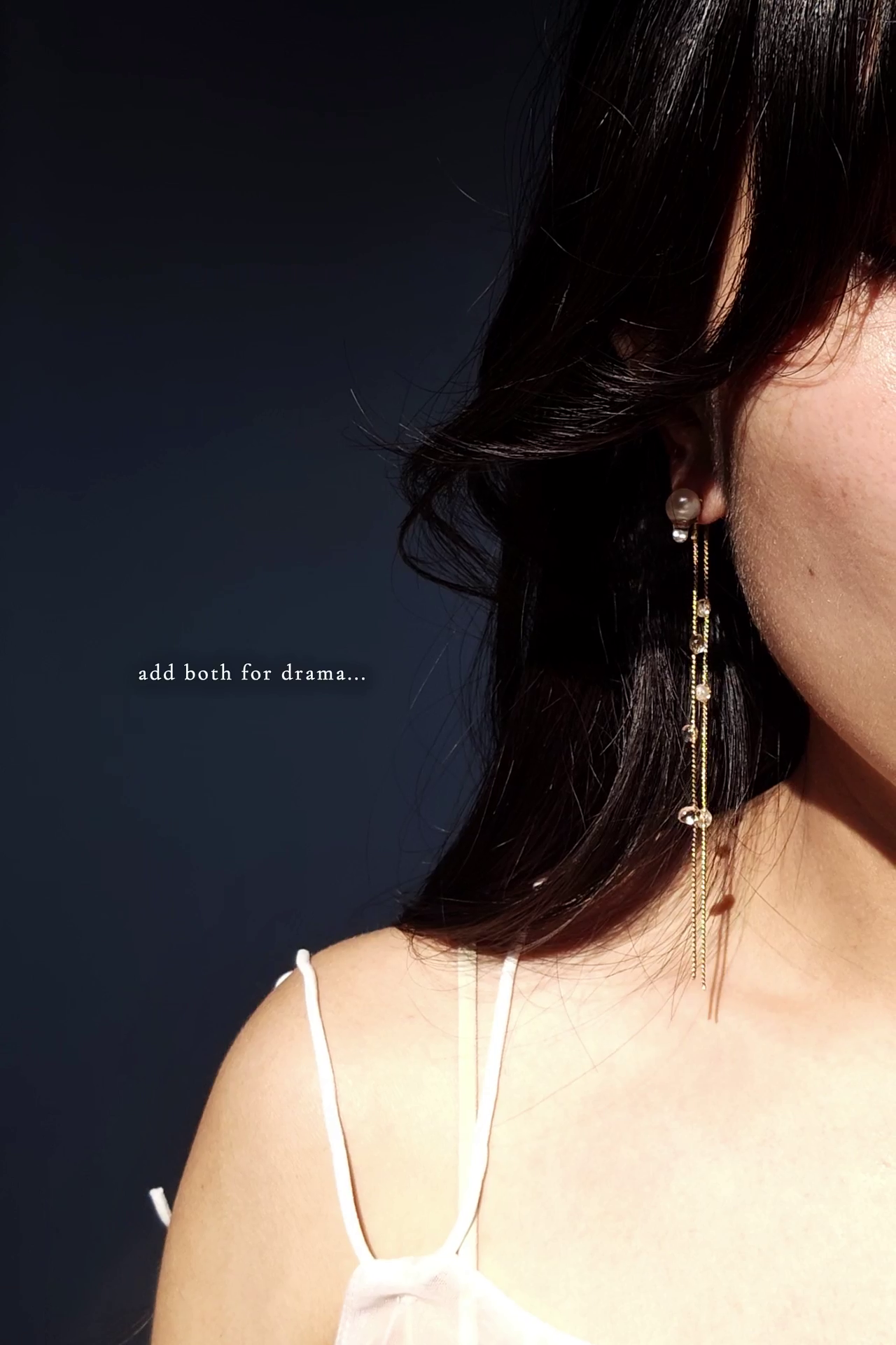 Close-up of a person wearing a HISEN aqua multiway earrings in gold against a dark background