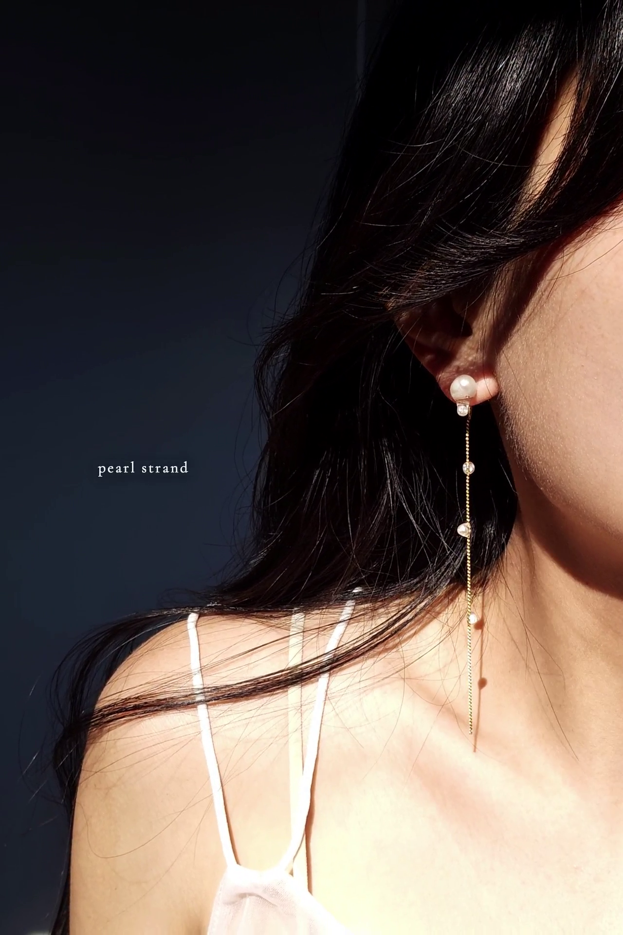 HISEN aqua drop earring with a pearl strand worn by a person with a dark background
