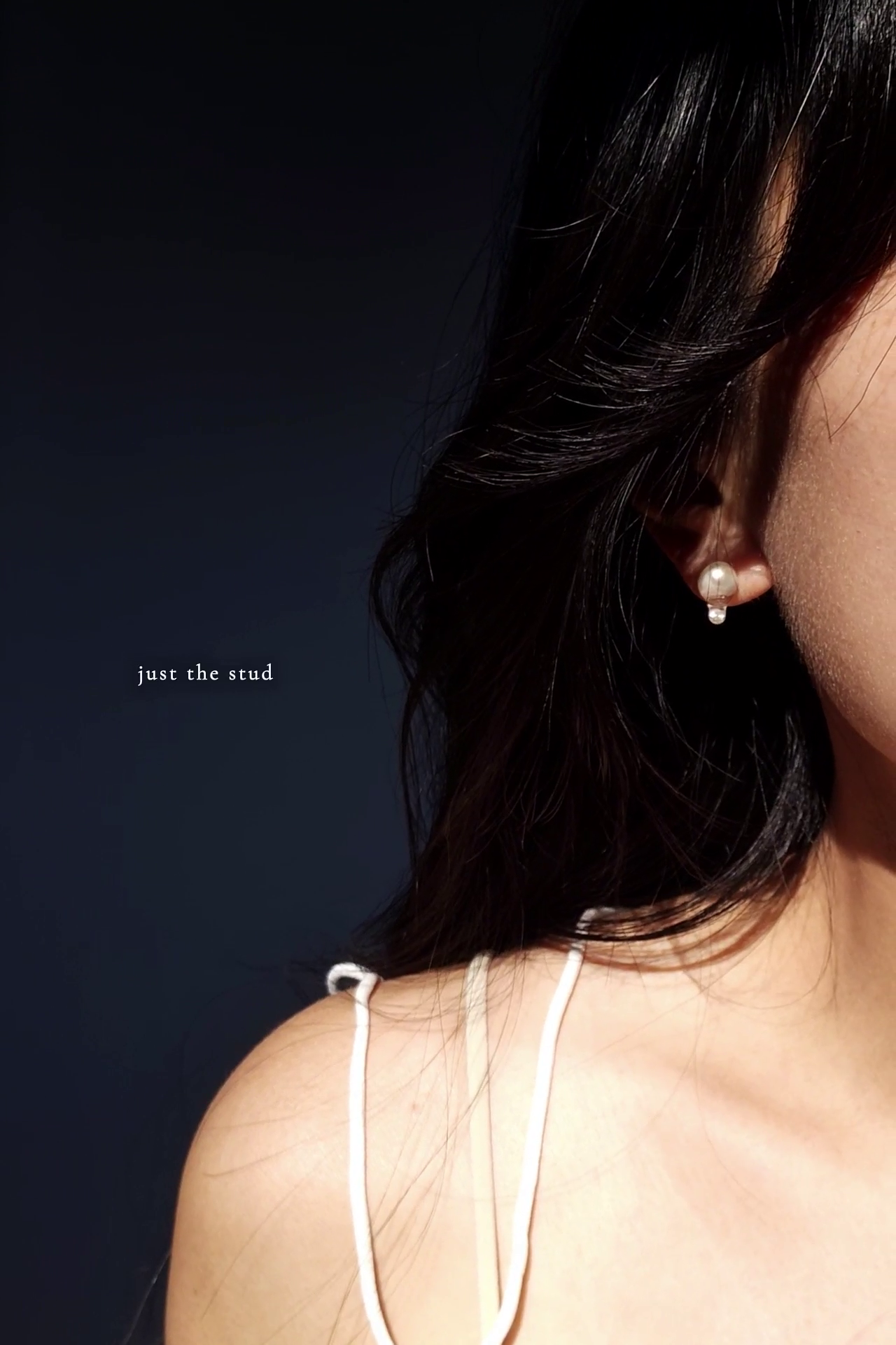 Close-up of a person wearing a pearl stud from HISEN aqua against a dark background with 'just the stud' text.