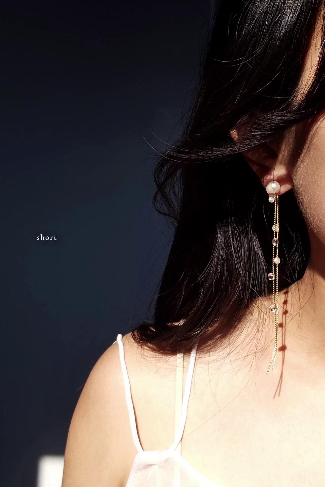 Close-up of a person wearing a delicate chain earring in gold, HISEN aqua, short version