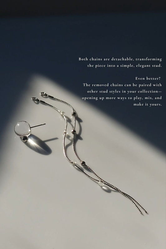 the detachable chains of the HISEN silver multiway drop earring laid on a flat surface