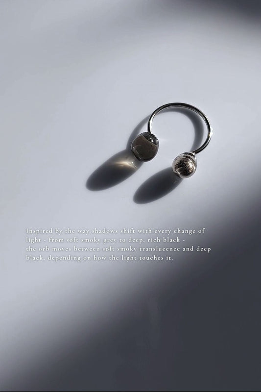 Double orb ring in translucent black and silver on flat surface
