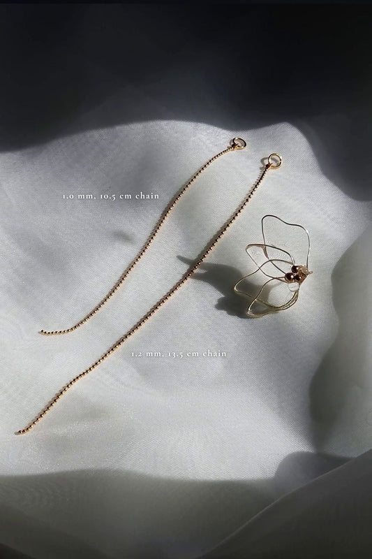 Delicate clear flower drop earring with gold chain, MEIKA gold chain drop, on a flat surface with parts description.