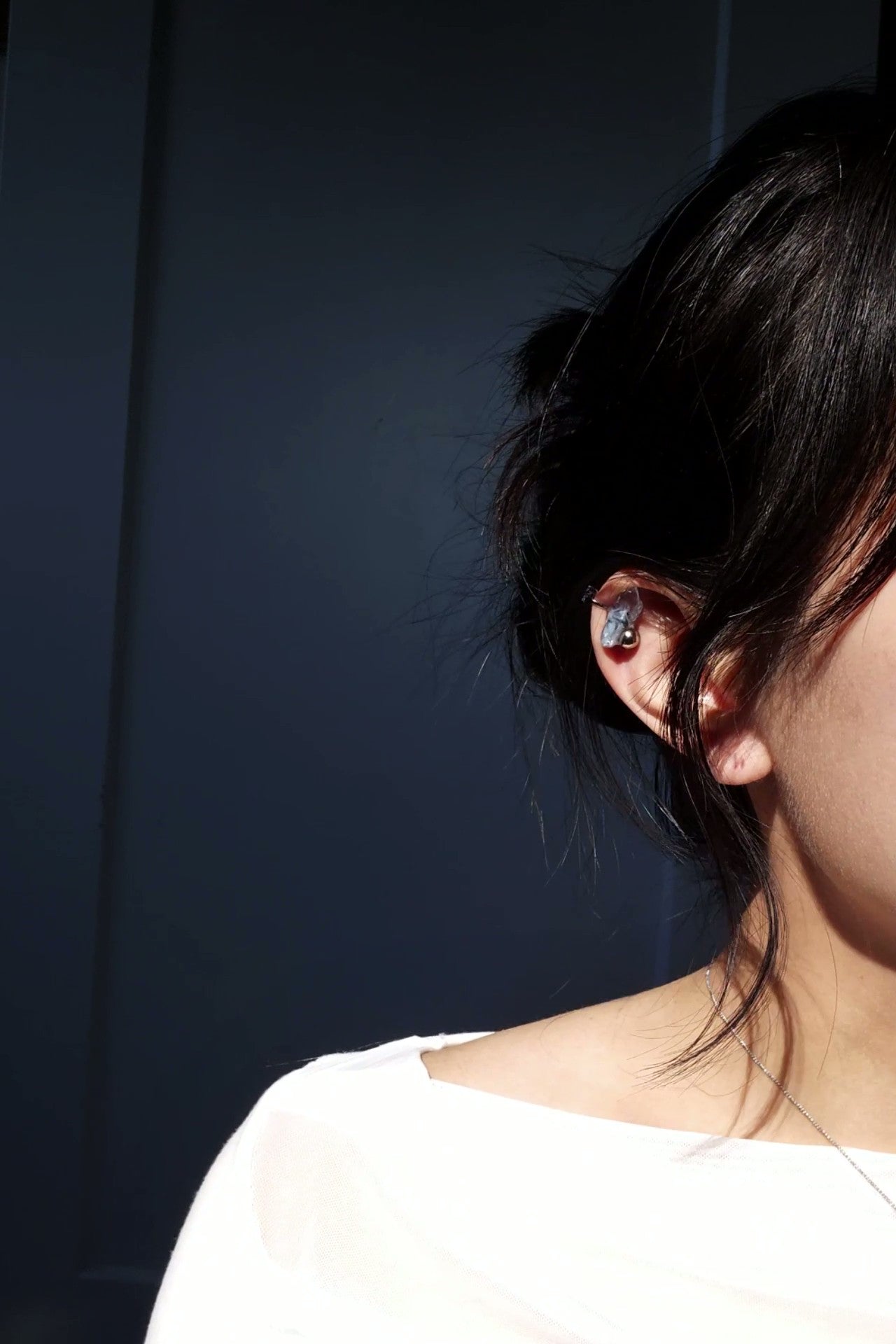 Model wearing NAMI ear climber on helix, elegant silvery blue-gray stone with silver orb.