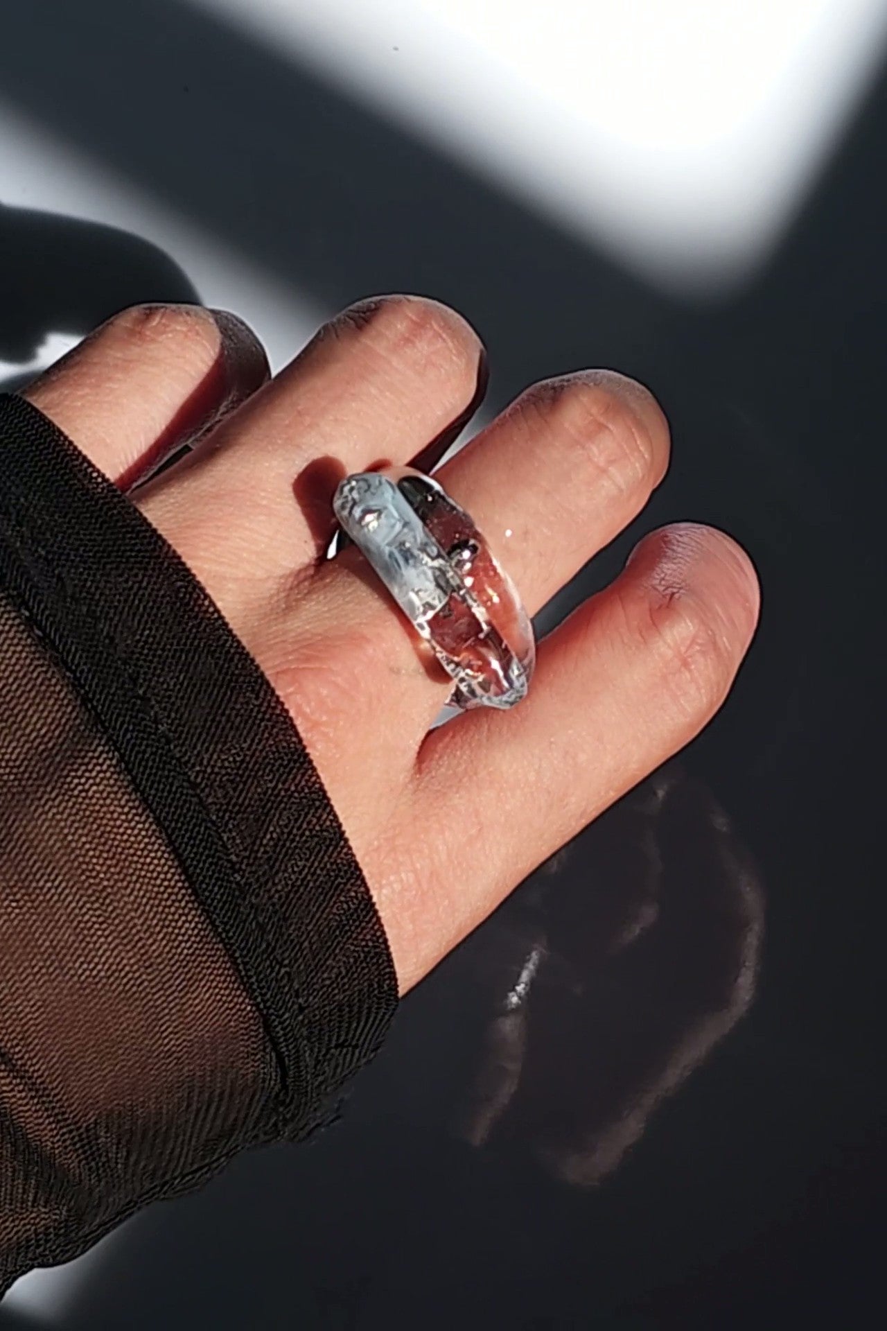 Close-up of a model wearing NAMI silvery blue ring stacked with TORORI silver ring, showcasing the sculptual look.