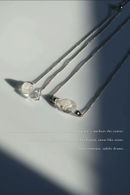 REI silver multiway necklace is laid flat showcasing hand-molded unique centerpiece stones and small stones that resembles like melting ice at the end of the chain.