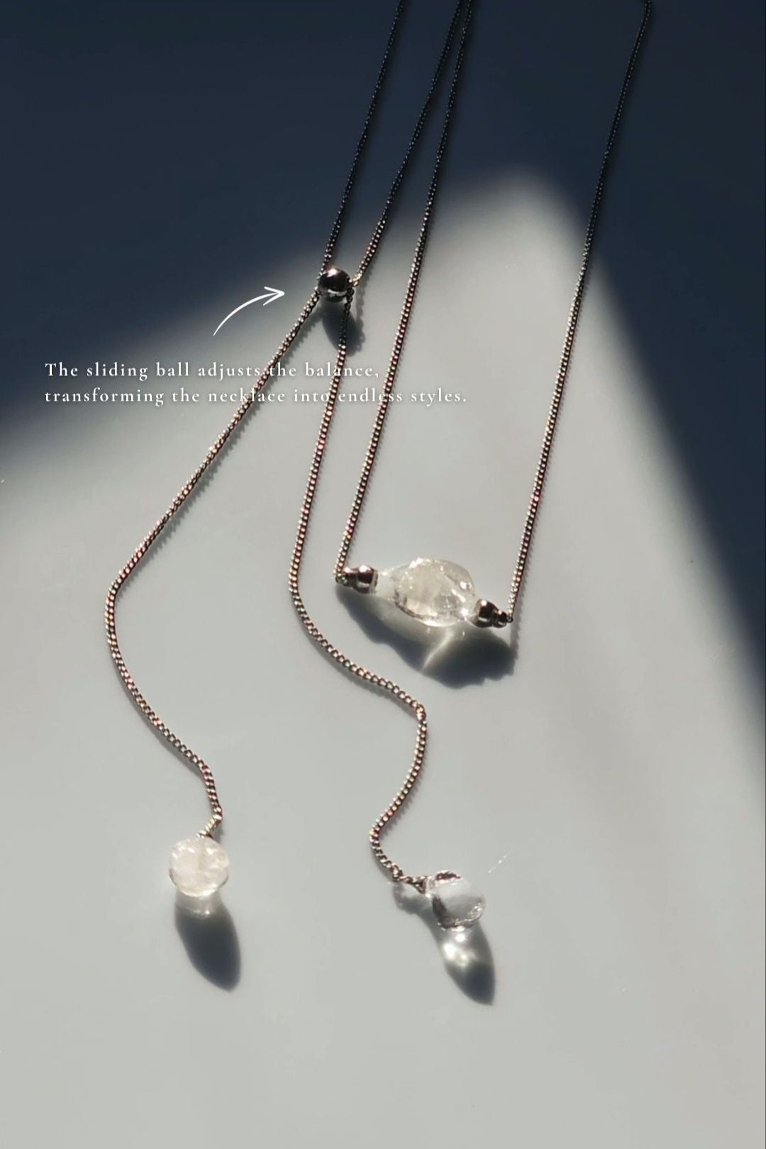REI silver multiway necklace laid flat showcasing the slide ball that make the piece tranform into different styles.