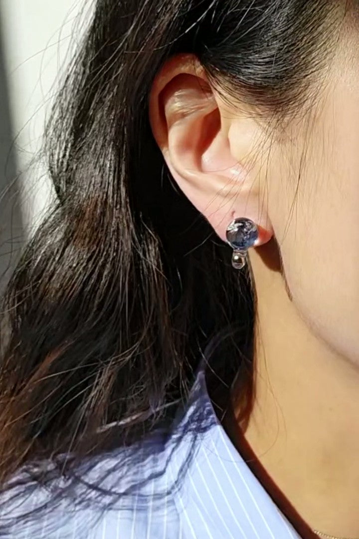 Model wearing SORA short drop earring, only the stud part. The hand-blended blue orb changes color with the light.