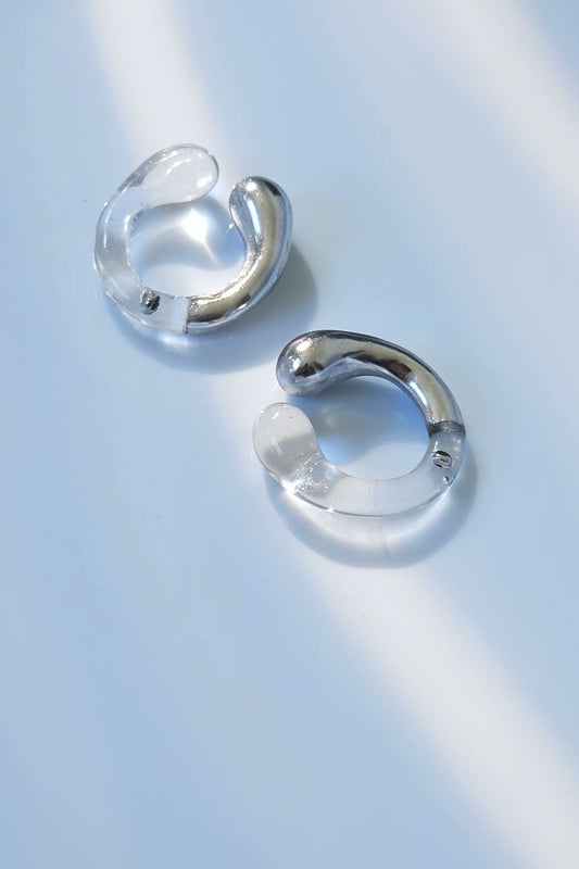 TORORI silver multiway ring with sculptural clear resin design, inspired by dripping water, shown laid on neutral background.