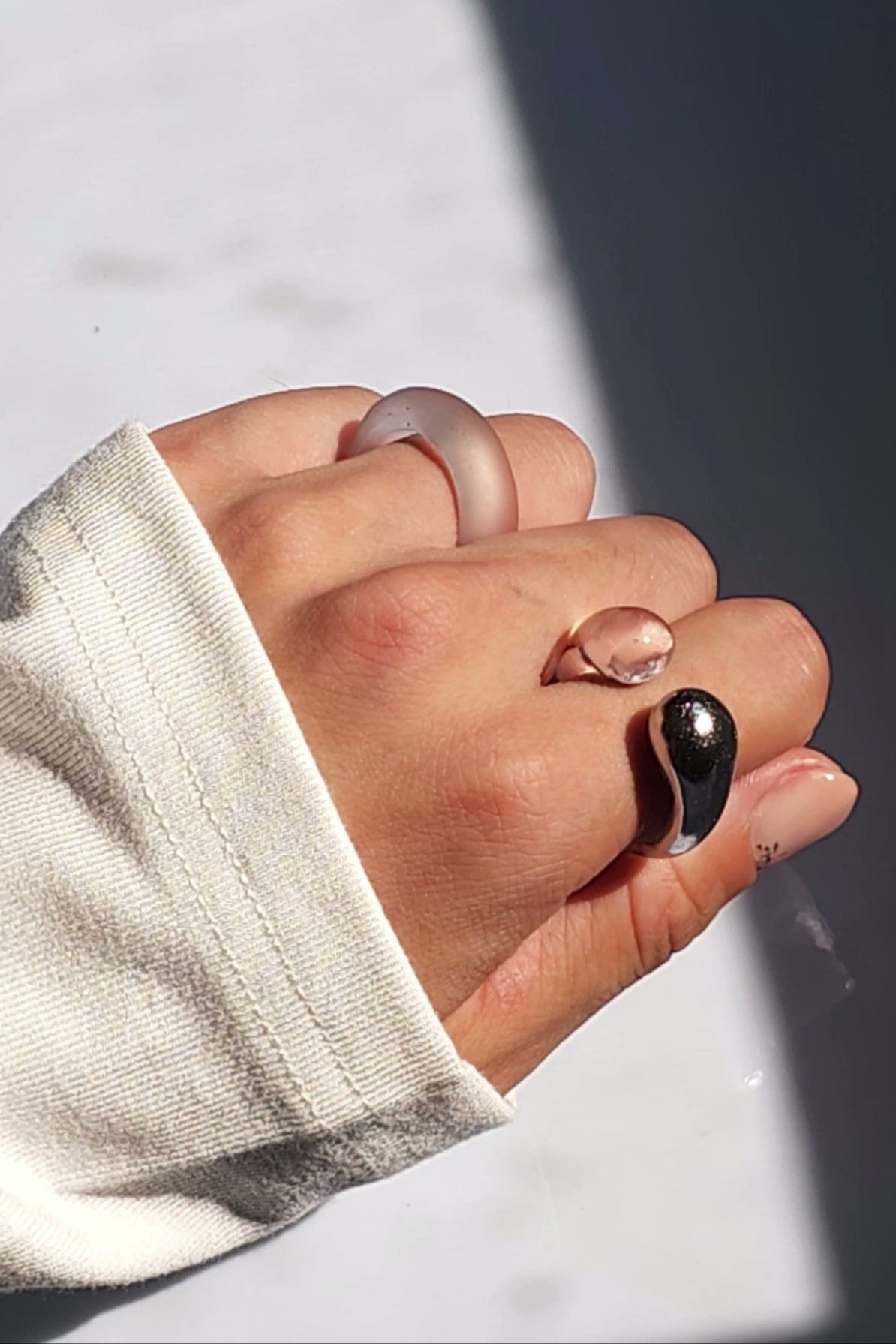 Model wearing TORORI silver as a ring on the index finger and KIRI frosty ring on the ring finger, showcasing a sculptural look.