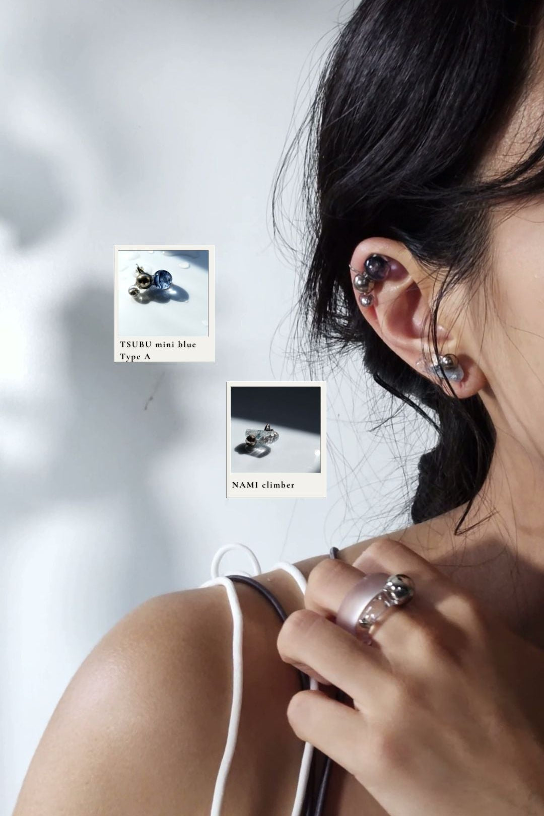 Close-up of a model wearing NAMI climber on earlobe, TSUBU mini blue orb climber on helix.