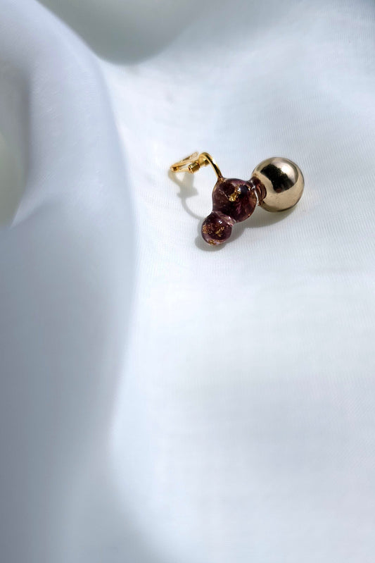 A flatlay picture of the TSUBU mini cherry climber features a hand-blended dark cherry orb with a simple gorden orb. Wear it as an climber or helix ear cuff.