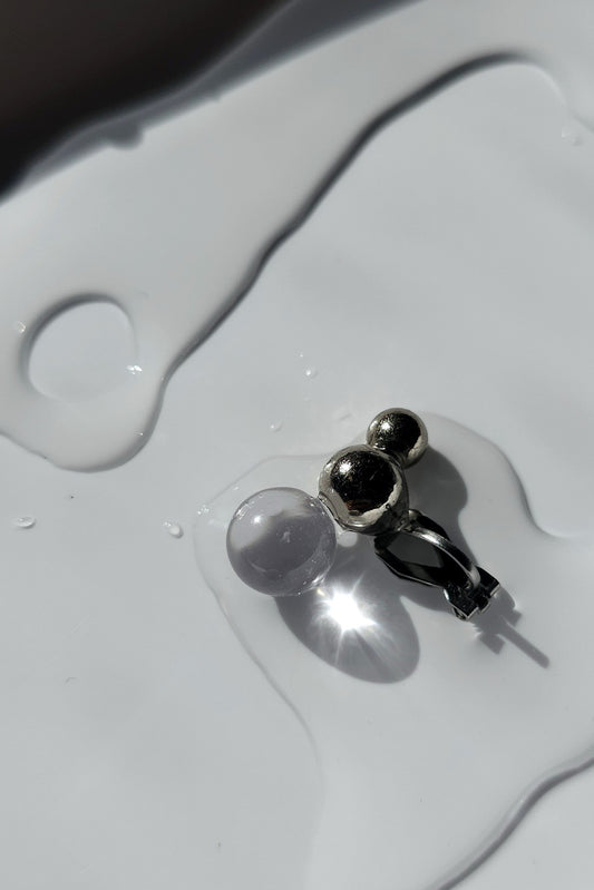 A flatlay of the TSUBU mini fusion climber (ear cuff) with a clear orb and silver orbs. No piercing required.