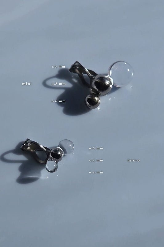 TSUBU mini fusion clear orb and silver orb earcuff compared with TSUBU micro fusion on a flat surface