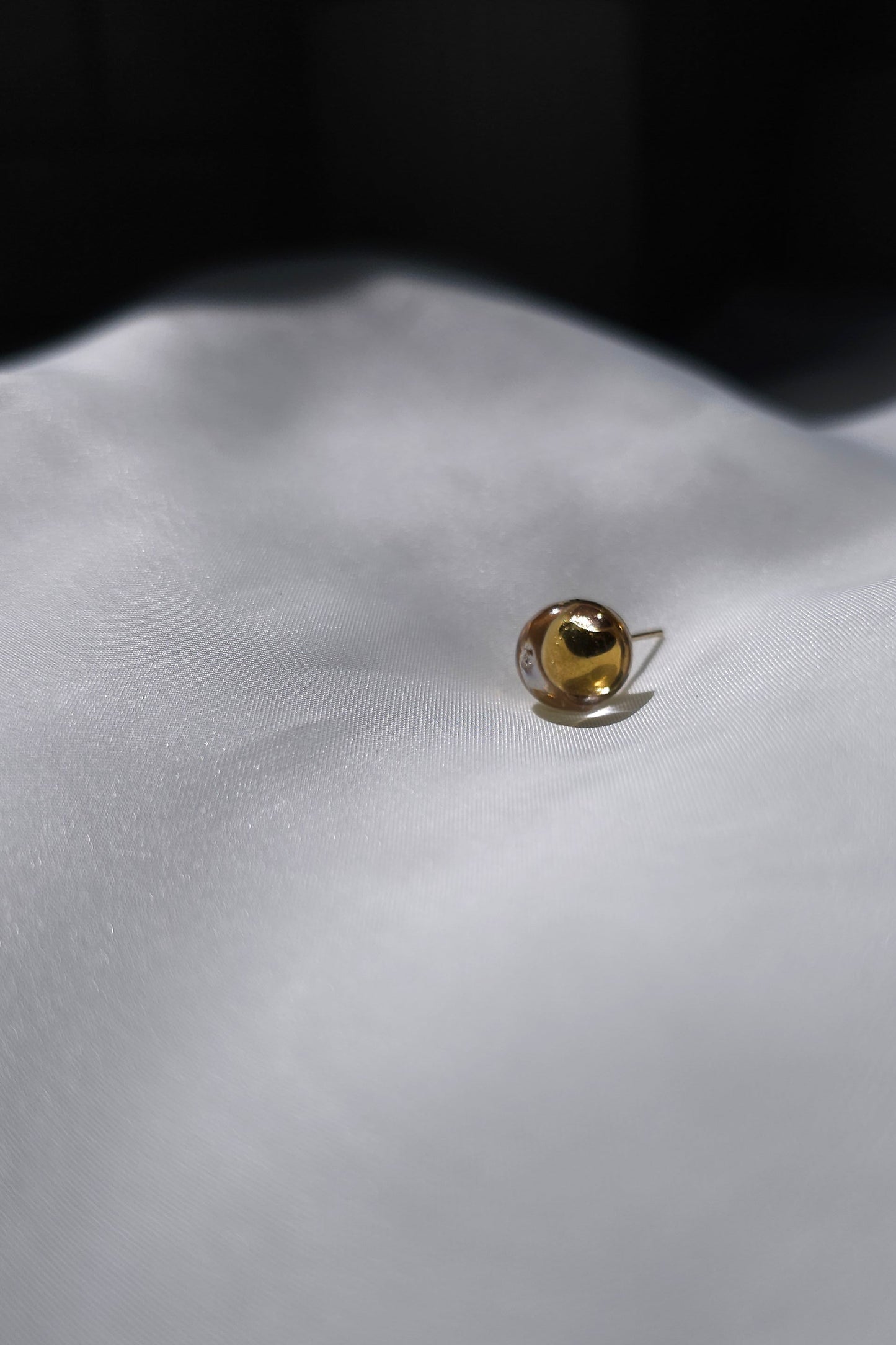 TSUYU gold stud earring, inspired by shimmering beads of dew, with warm golden reflections that change in the light.