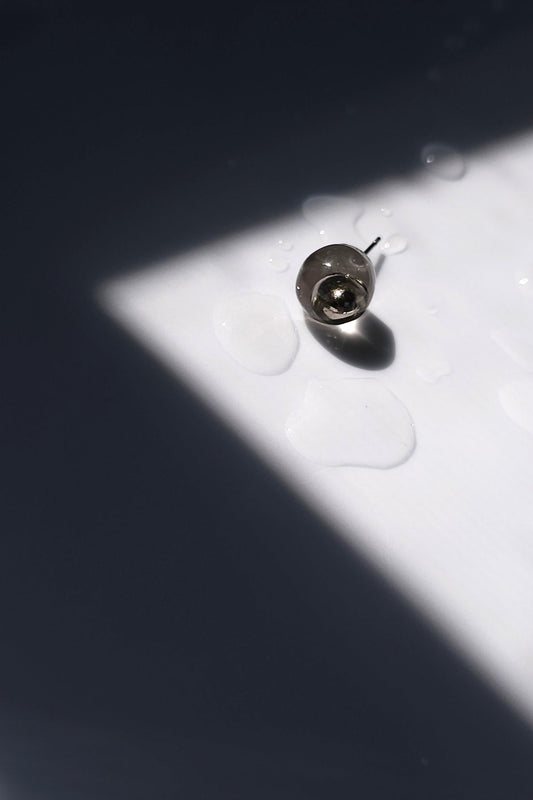 TSUYU silver stud earring, inspired by morning dew, with reflective clear and silver tones that shift with light.