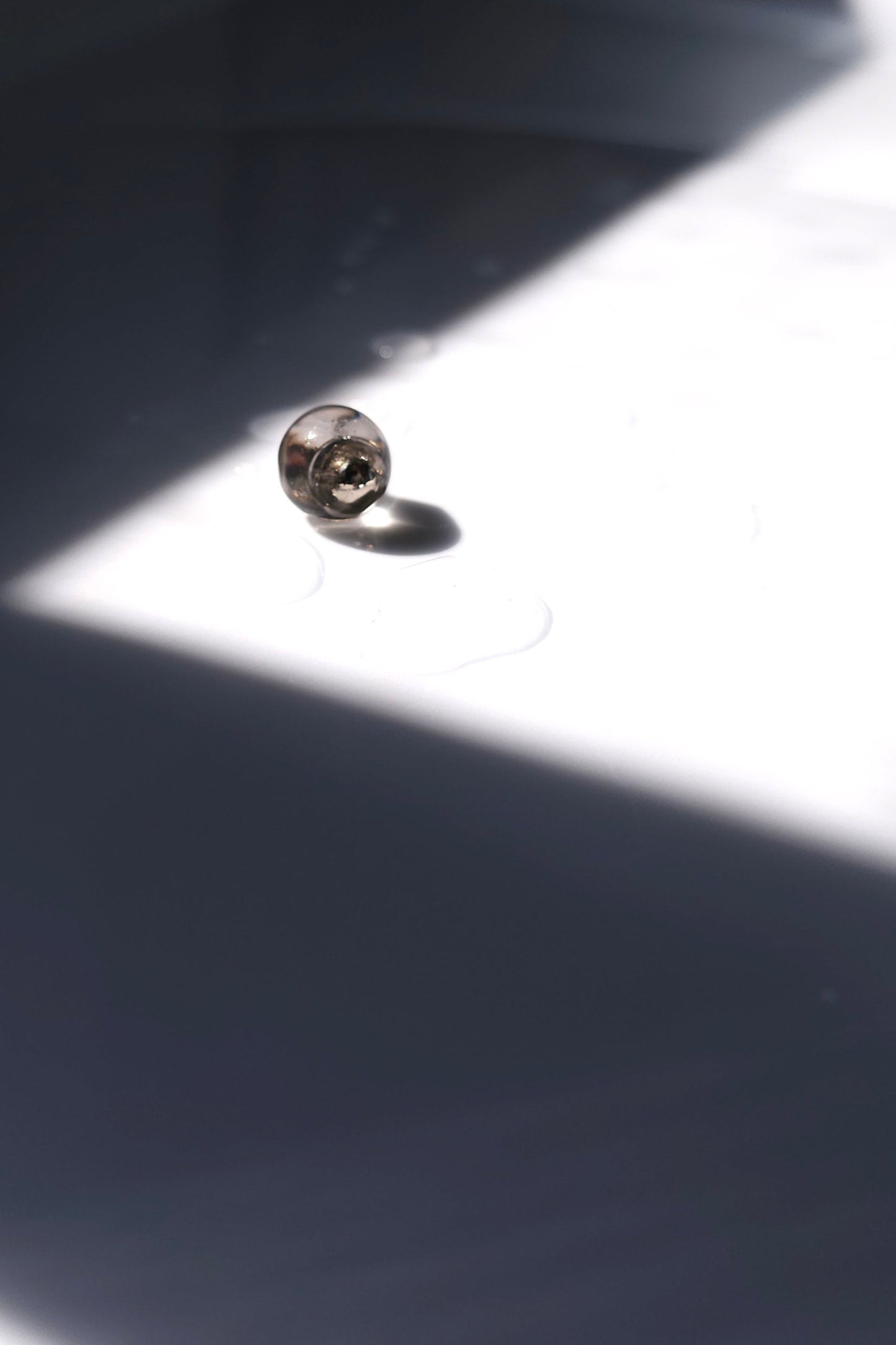 TSUYU silver stud earring, inspired by morning dew, with reflective clear and silver tones that shift with light.