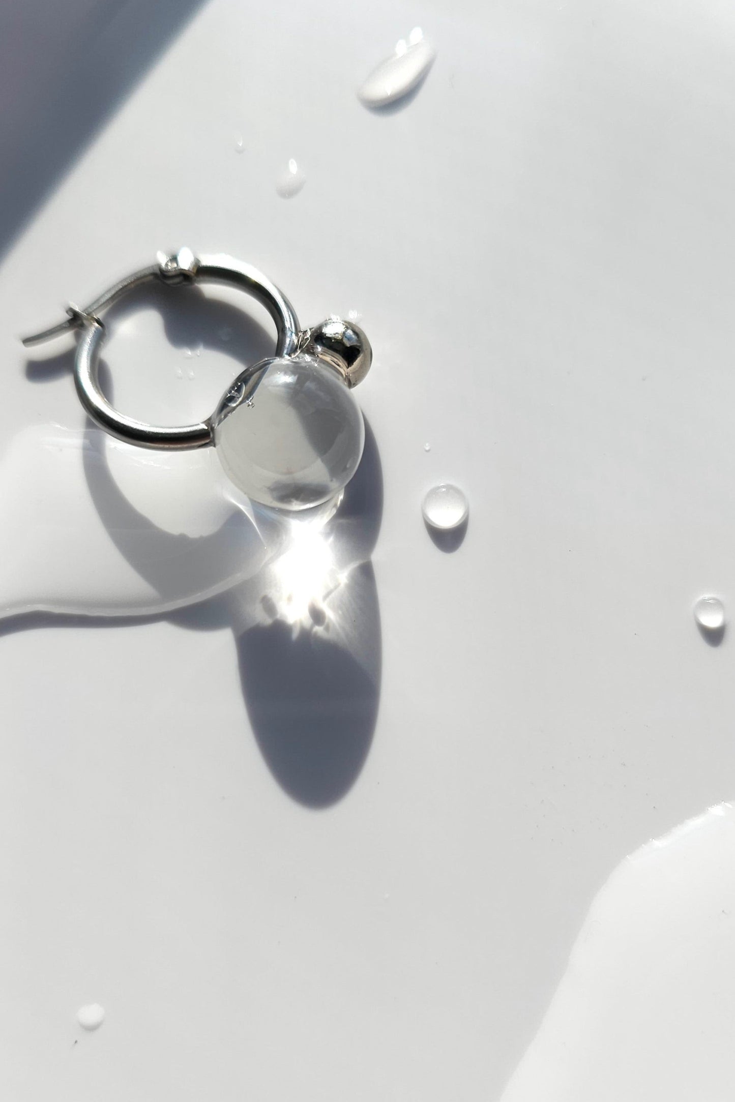 YOTSUYU silver earrings with translucent and clear orb on silver hoop, inspired by night dew under moonlight, lightweight and luminous huggie.