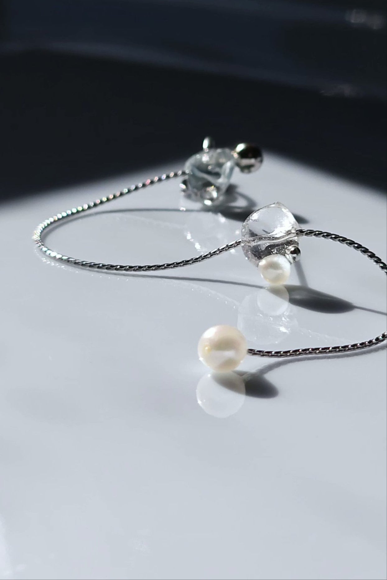 NAMI multiway ear cuff and stud connected by chain with freshwater pearls, featuring hand-blended silvery-blue and gray tones inspired by ocean waves.