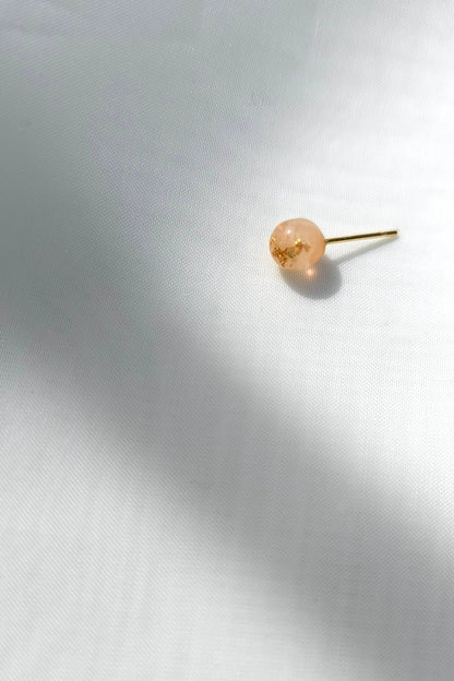 A single 6mm orb stud in orange beige tone, HARU micro stud, on a flat surface