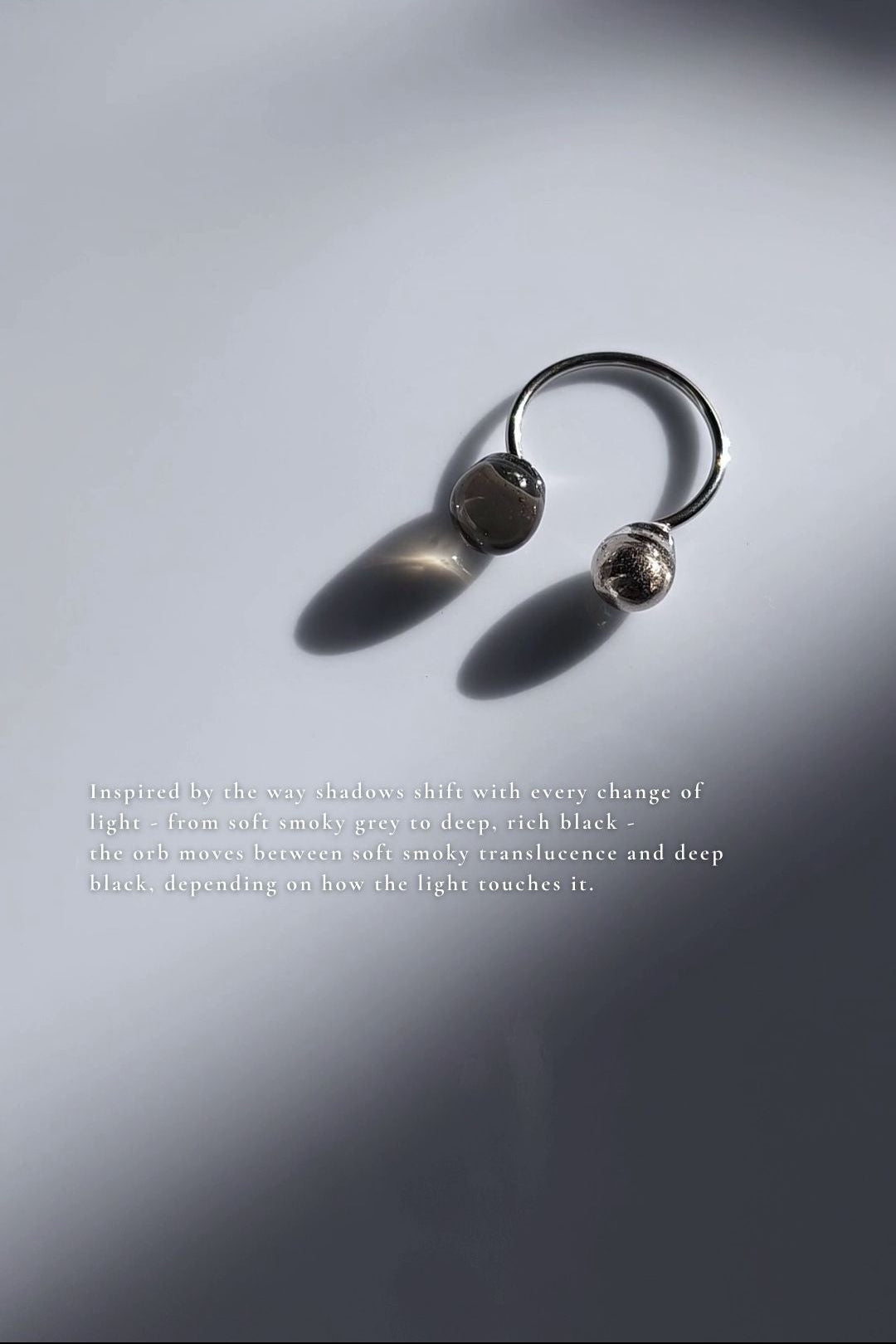 Double orb ring in translucent black and silver on flat surface