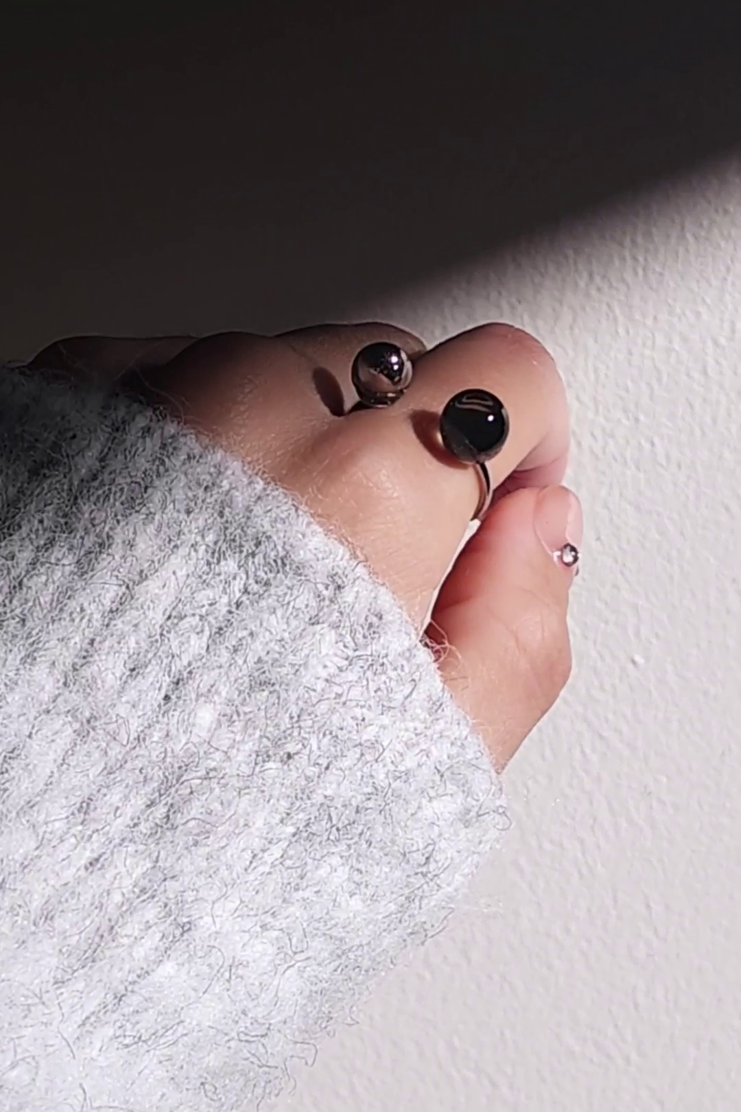 Close-up of a hand wearing double orb ring in translucent black and silver, KAGE double ring, on the index finger.