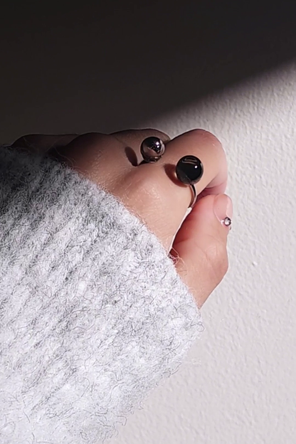 Close-up of a hand wearing double orb ring in translucent black and silver, KAGE double ring, on the index finger.