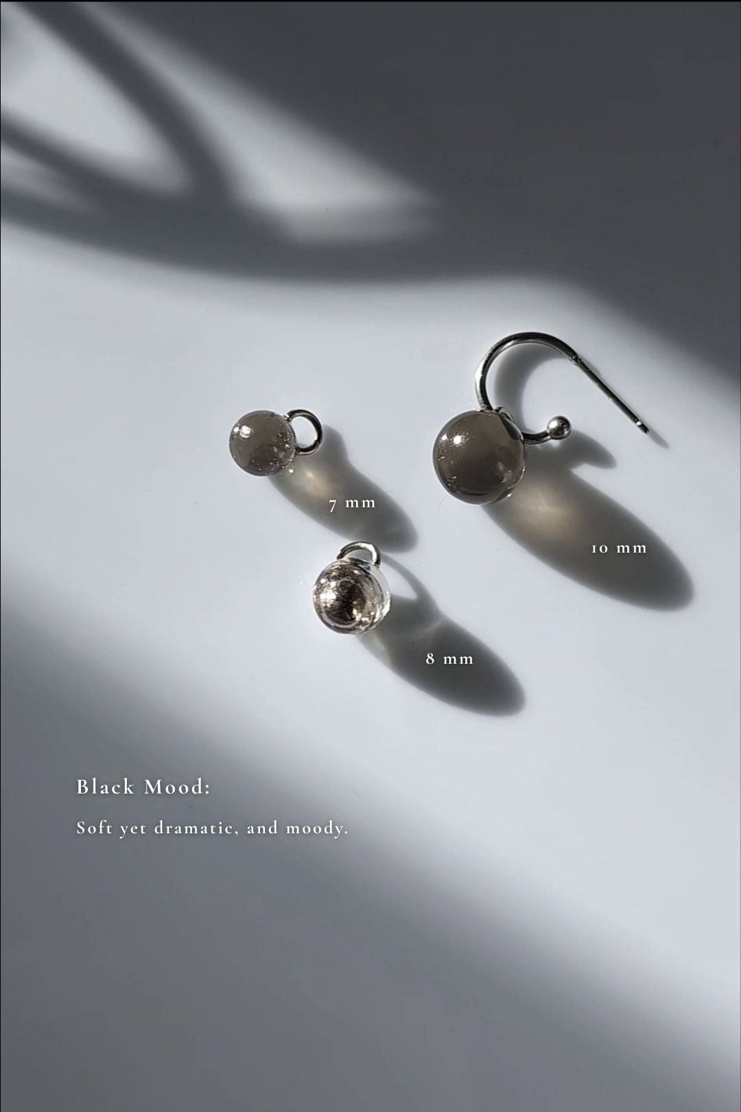 Three orb hoop earring, KAGE multiway hoop on the flat surface, showcasing 10mm and 7mm translucent black orbs, and 8mm silver orb.