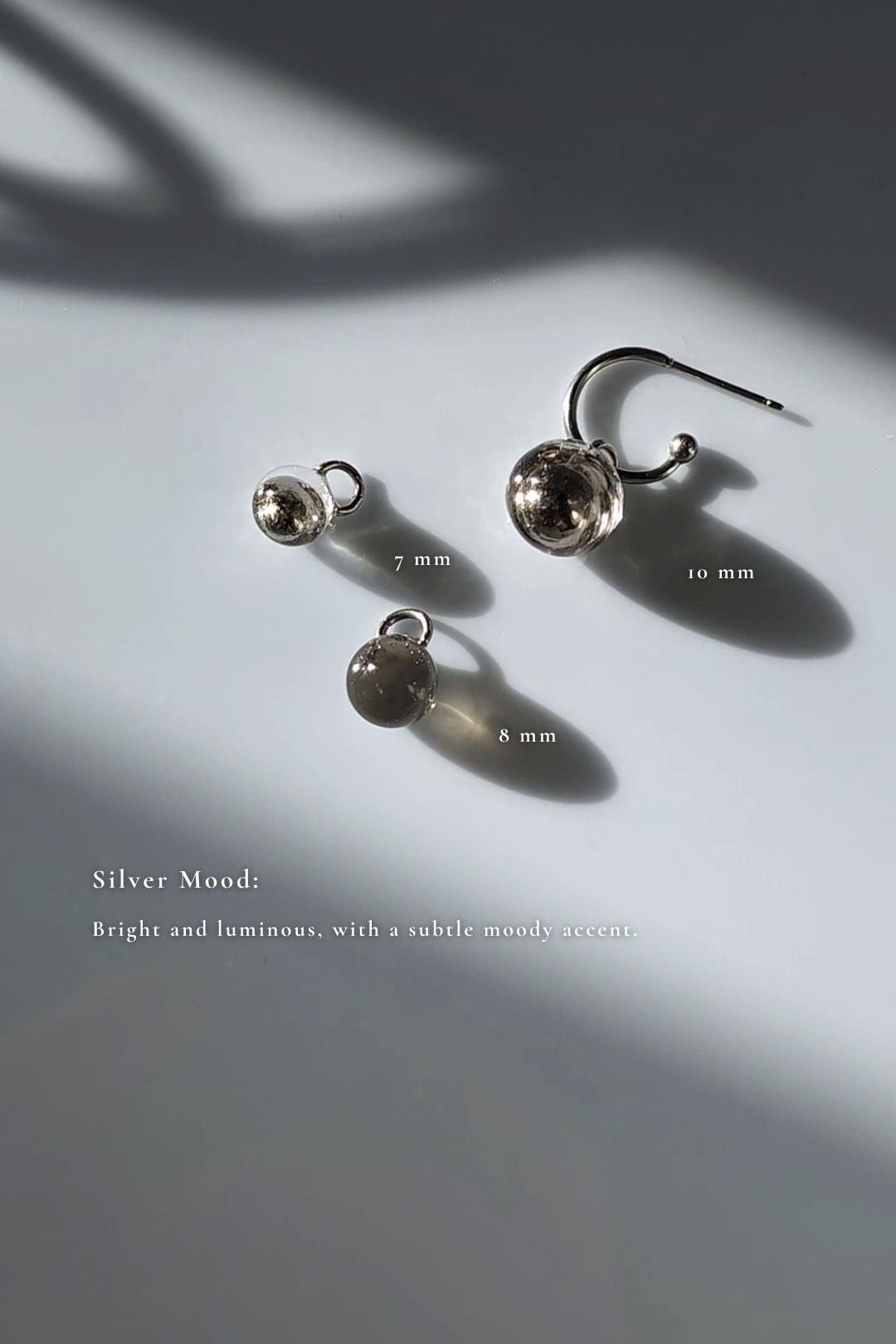 Three orb hoop earring, KAGE multiway hoop on the flat surface, showcasing 10mm and 7mm silver orbs, and 8mm translucent black orb.