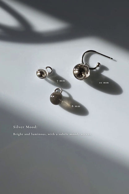 Three orb hoop earring, KAGE multiway hoop on the flat surface, showcasing 10mm and 7mm silver orbs, and 8mm translucent black orb.