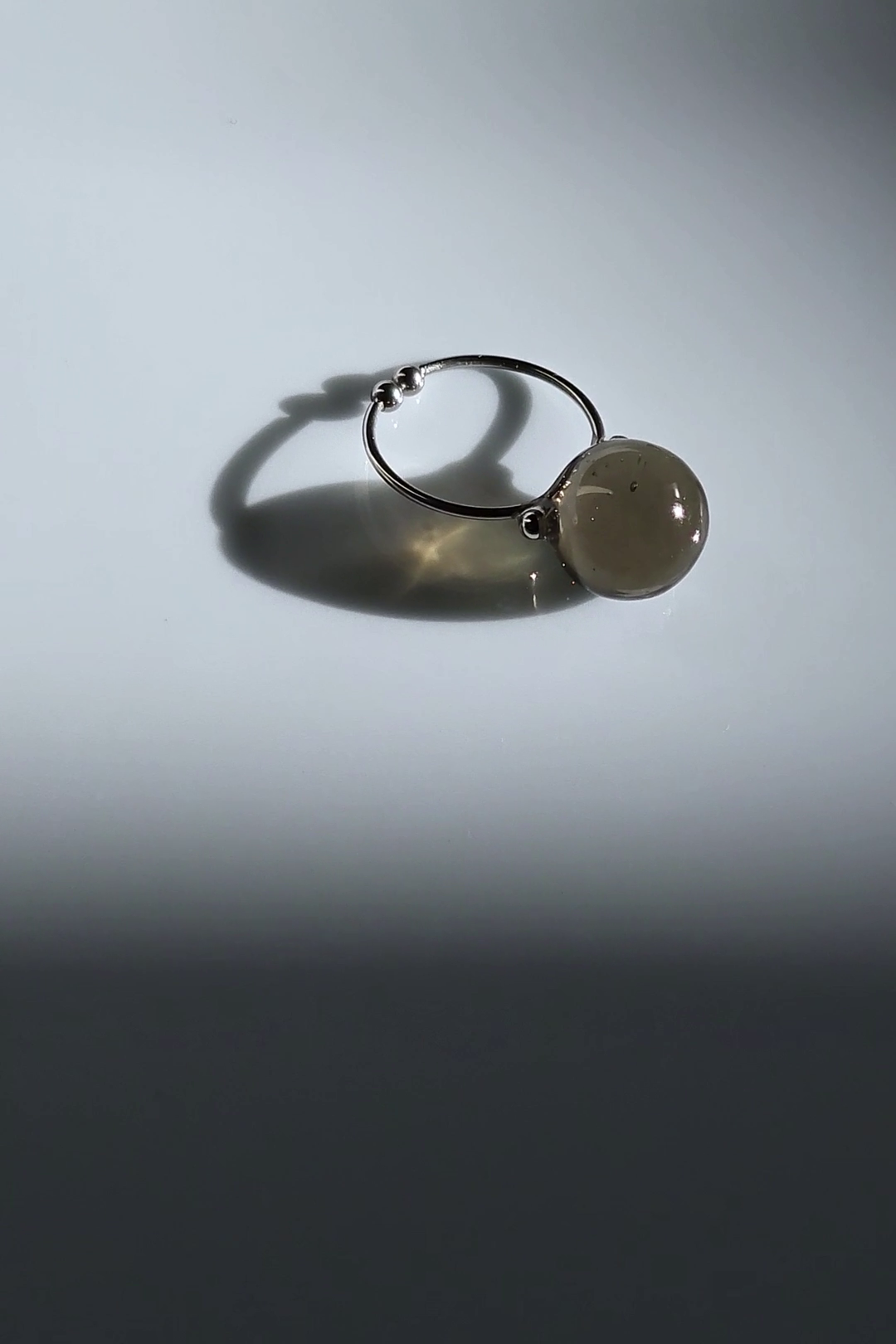 12mm translucent black orb on silver ring, KAGE silver ring on flat surface.
