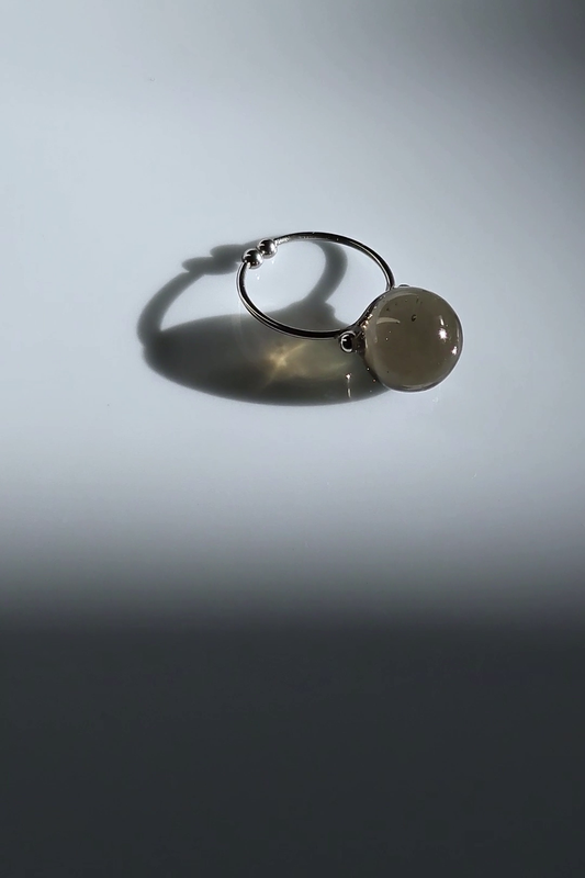 12mm translucent black orb on silver ring, KAGE silver ring on flat surface.