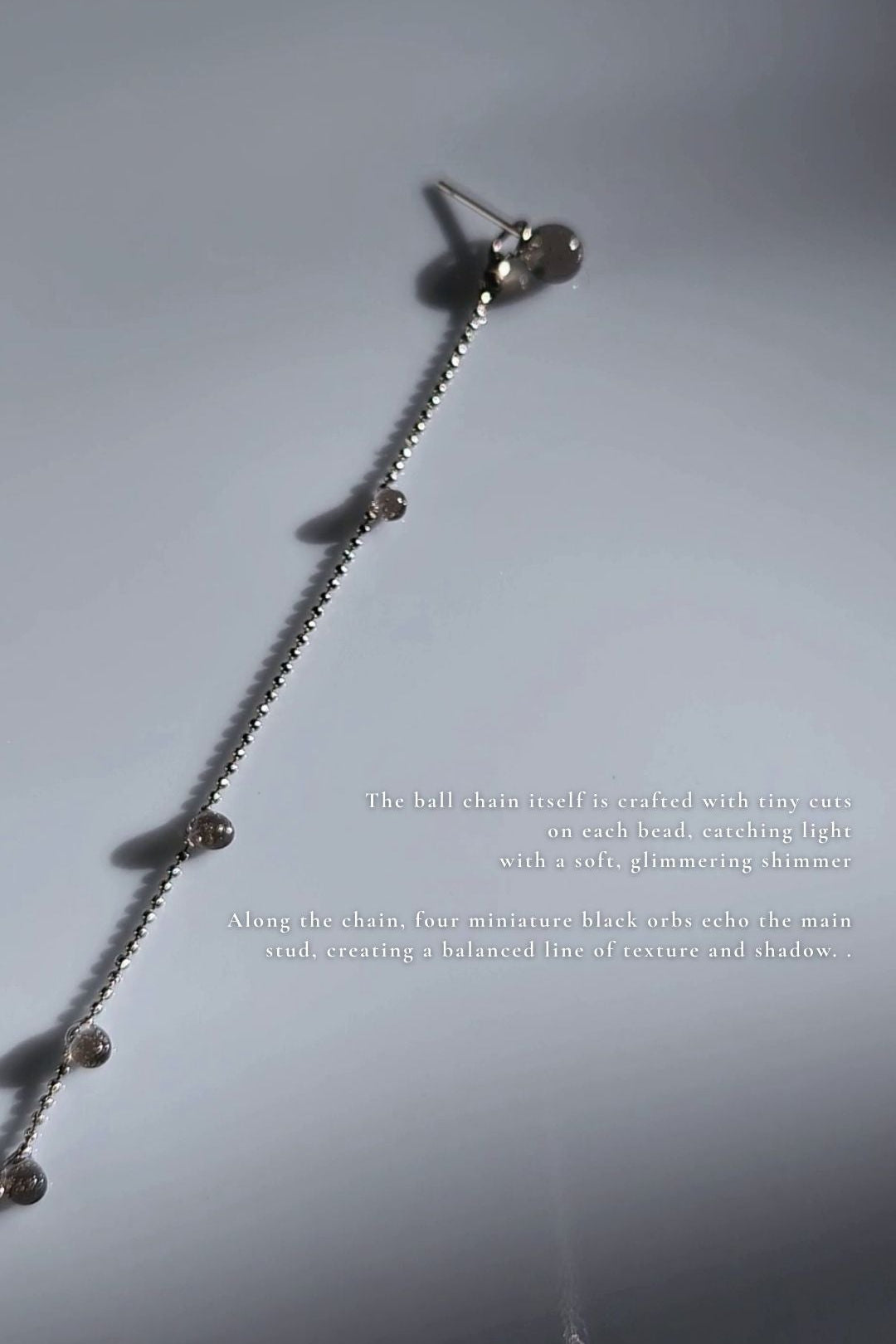 close-up of translucent black orb chain drop, KAGE silver chain drop.