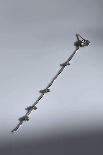 Delicate chain drop with translucent black orbs, KAGE silver chain drop on a flat surface.