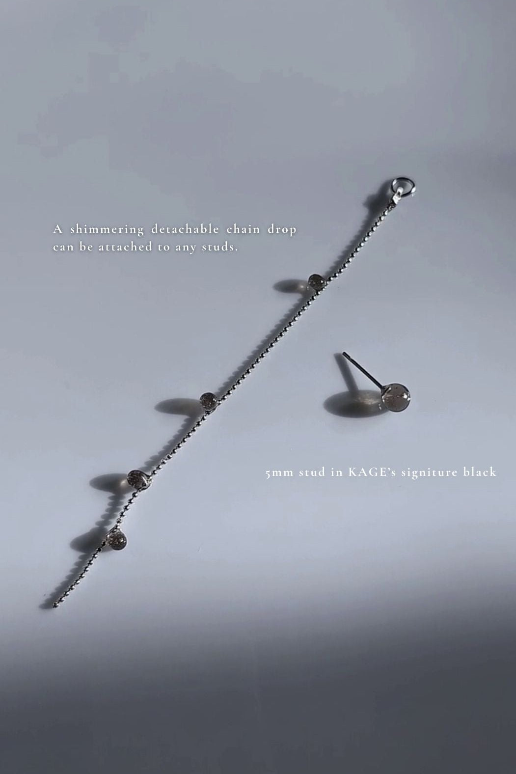 Silver earring with translucent black orbs, KAGE silver chain drop on a light gray background