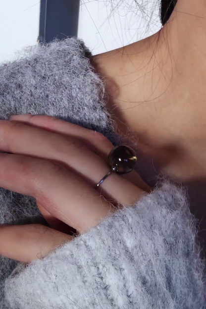 A model wearing KAGE silber orb ring, 12 mm translucent black orb silver ring on middle finger.