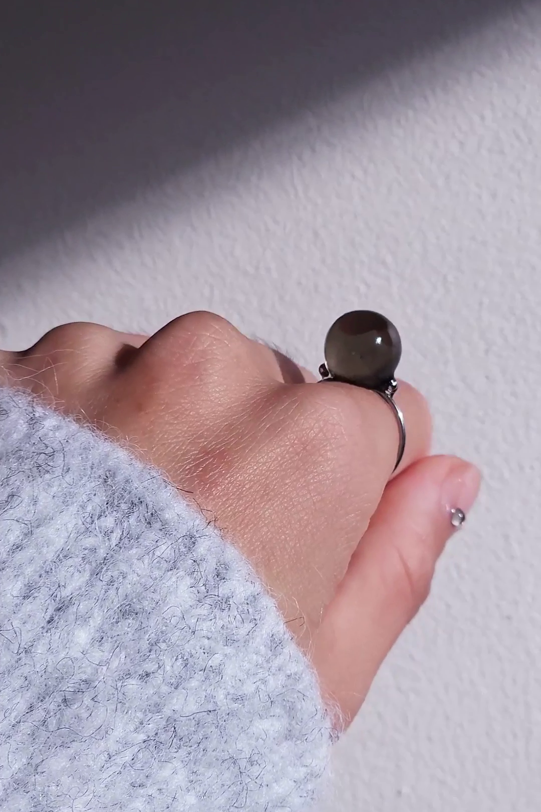 A model wearing KAGE silber orb ring, 12 mm translucent black orb silver ring on index finger.