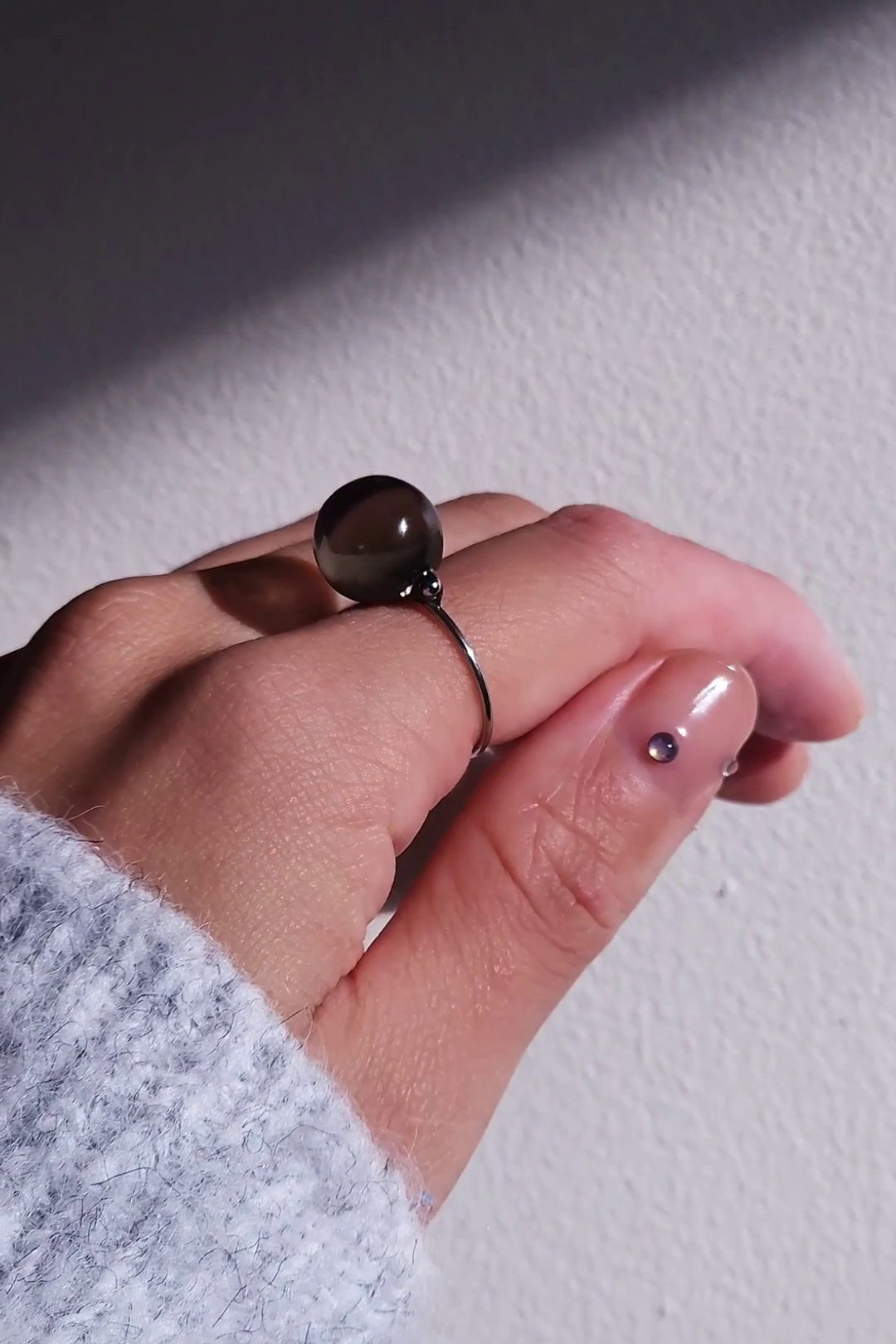 A model wearing KAGE silber orb ring, 12 mm translucent black orb silver ring on index finger.