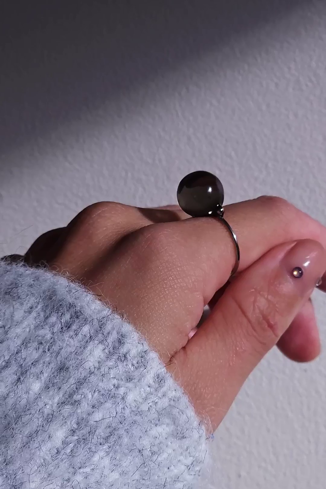 A model wearing KAGE silber orb ring, 12 mm translucent black orb silver ring on index finger.