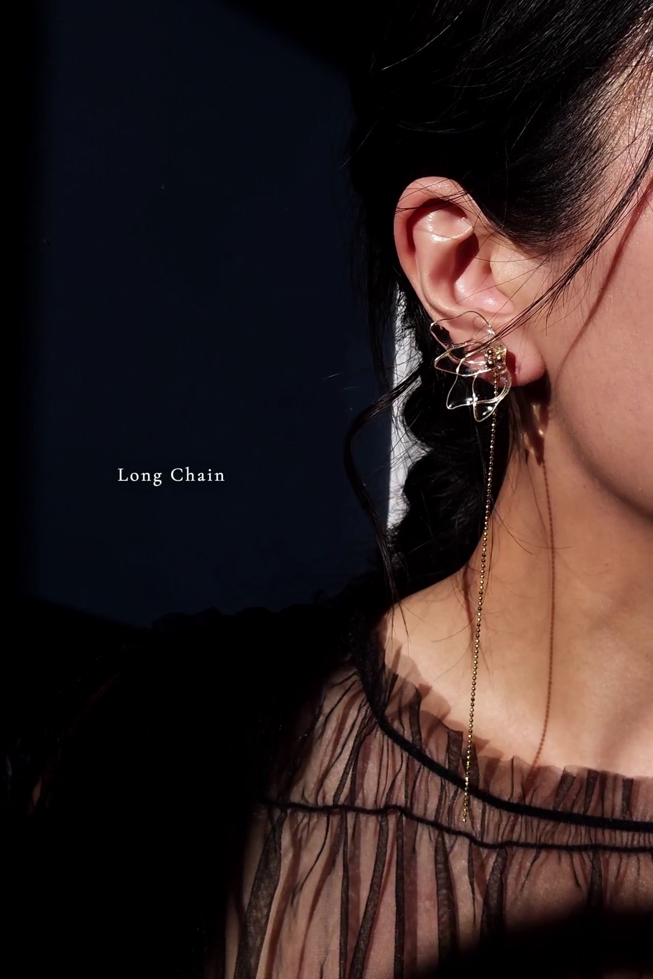 Model wearing clear floral earring in gold, MEIKA gold chain drop, with a long chain.