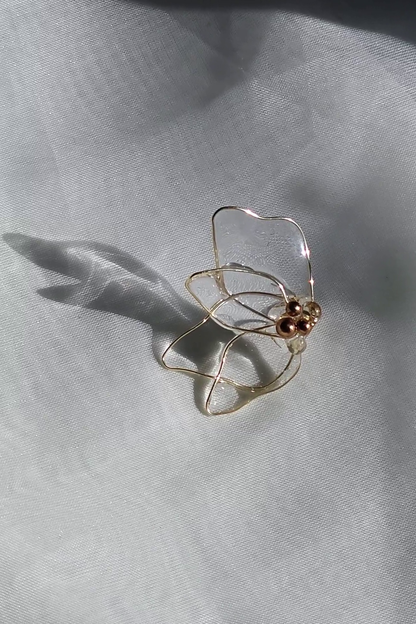 the flower stud part from MEIKA gold chain drop on a flat surface