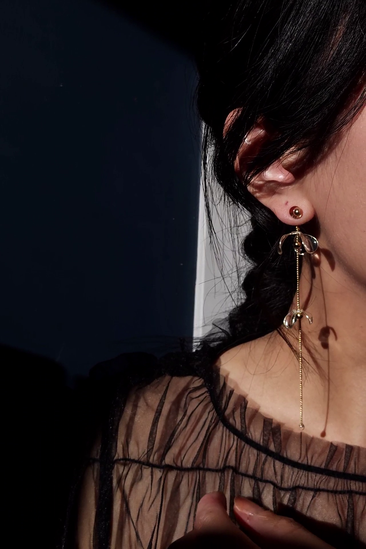Model wearing a clear flower drop with a gold accent, MEIKA gold long drop, with flowers set apart.