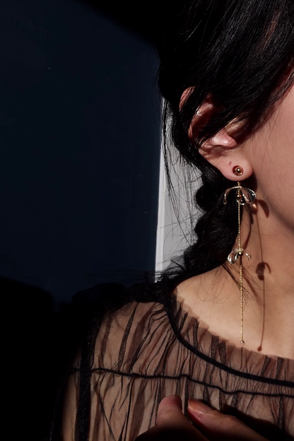Model wearing a clear flower drop with a gold accent, MEIKA gold long drop, with flowers set apart.