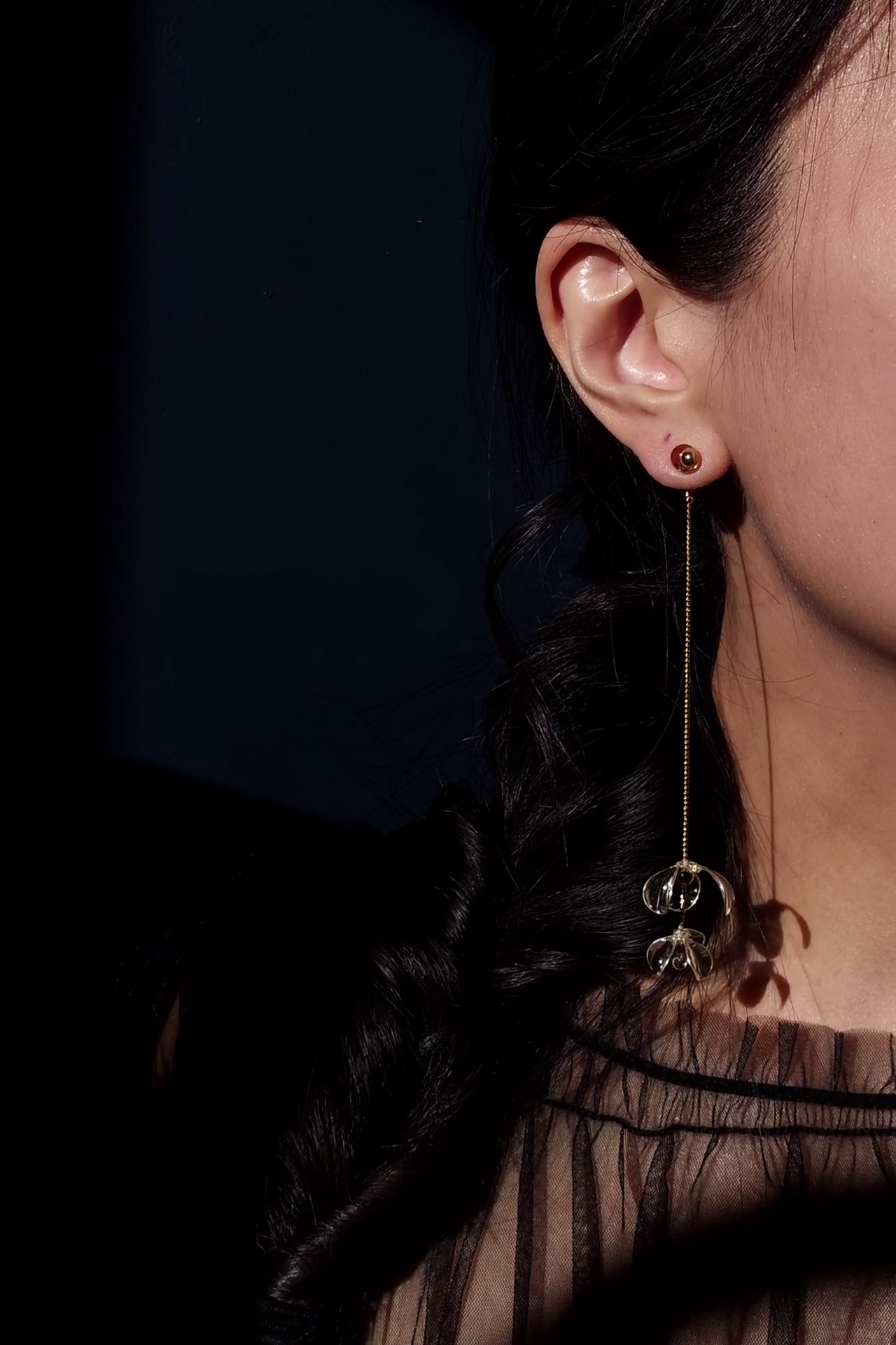 Model wearing a clear flower drop with a gold accent, MEIKA gold long drop, with flowers gathered at the bottom.