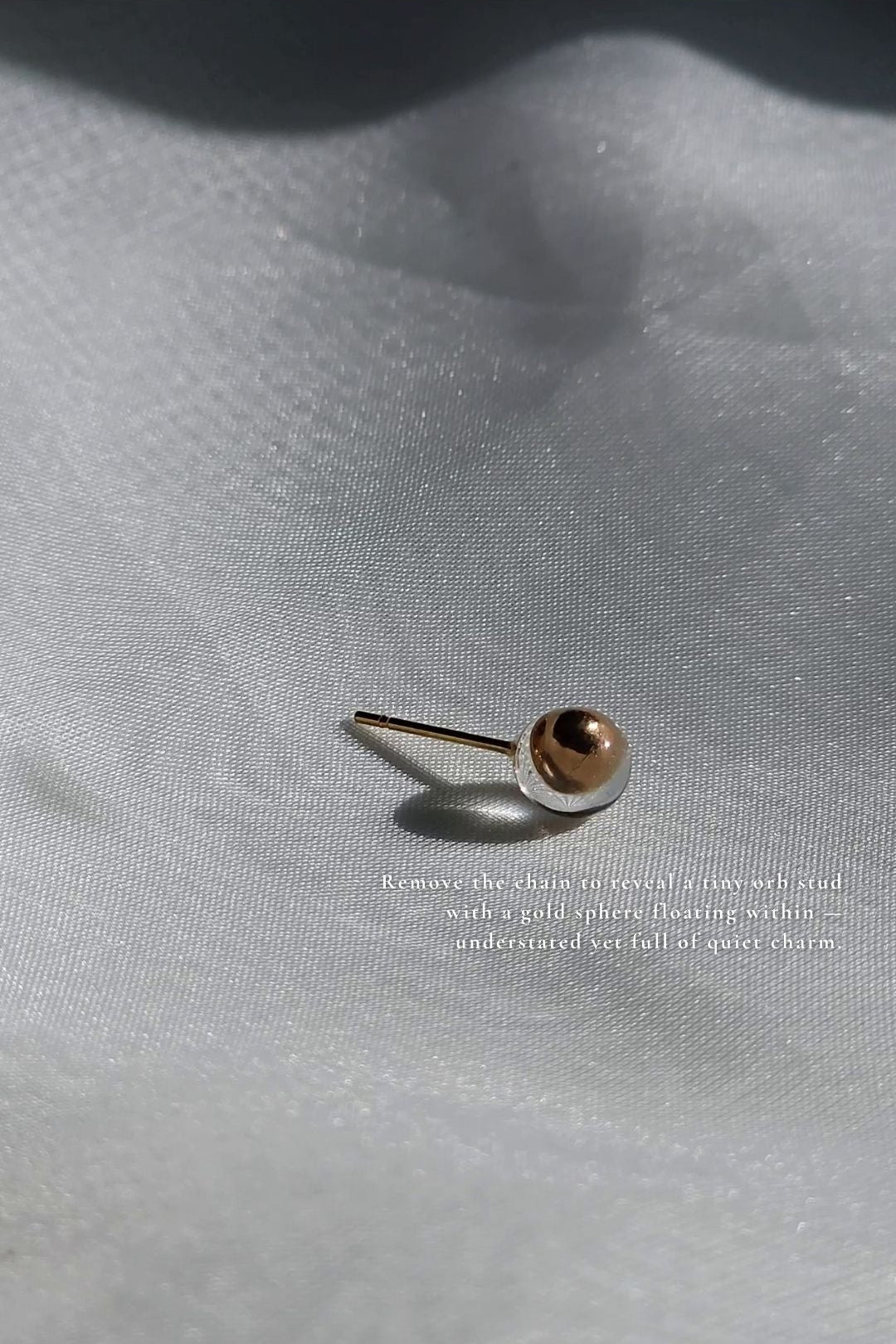 Golden orb stud from clear flower drop earring, MEIKA gold long drop, on a flat surface with details.