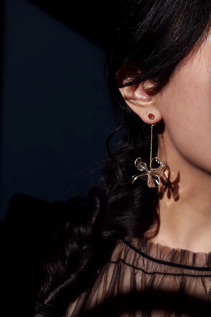 Model wearing clear flower drop earring with gold accent, MEIKA gold short drop, with the flower at the bottom of the chain.