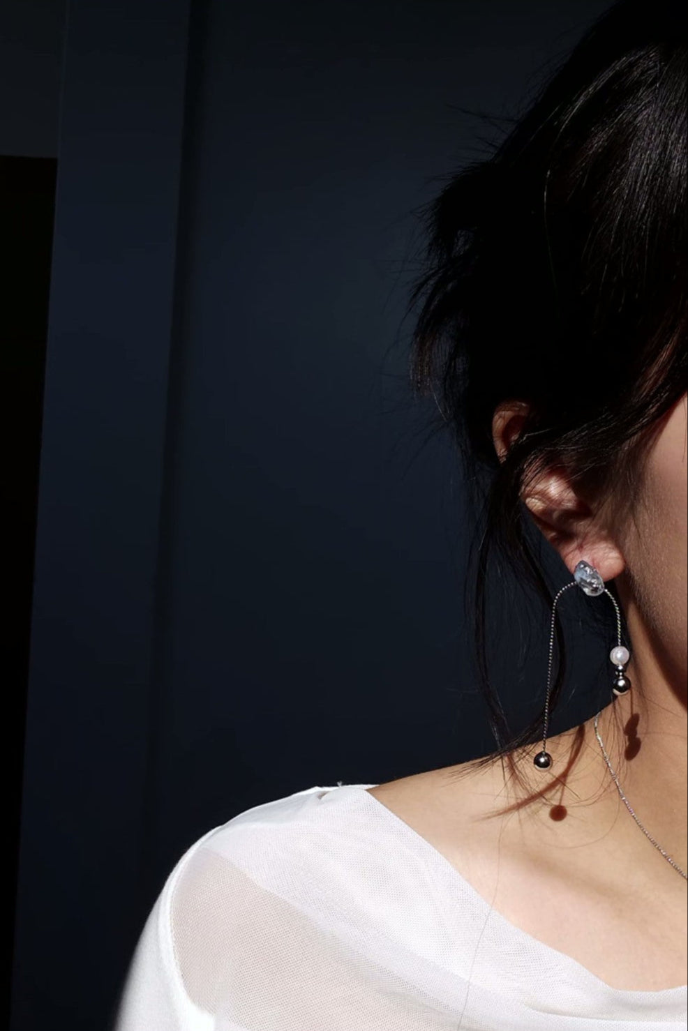 Model wearing NAMI multiway drop earring showcasing detachable chain, freshwater pearl, and fluid silvery-blue glow